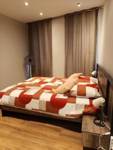 a bedroom with a bed with a orange and white comforter at Appartement 2 in Aubigny-sur-Nère