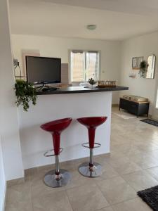 a kitchen with a bar with two red stools at Appartement Romana PUISSALICON 34 in Puissalicon
