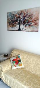 a painting of a tree on the wall above a couch at ROSA BLU House Ospedale Cisanello Pisa in Pisa +14 photos