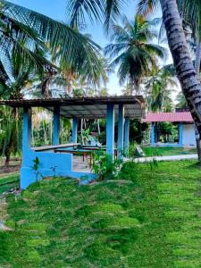 a blue building with palm trees in the background at Airport Coconut Villas Free Oneway Airport Pick Drop in Henpitagedara