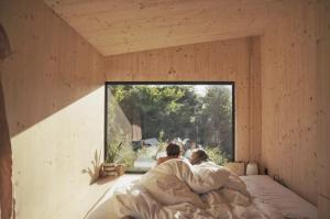 a couple laying in bed in a room with a window at Wild Cabins Kinvara in Cloonnasee
