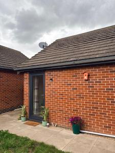 a brick building with potted plants in front of it at Clover Road Guest Suite in Swaffham