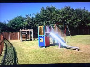 a playground with a slide in a yard at 2 Broadside Chalet Park in Stalham