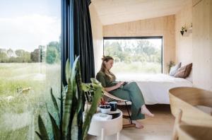 a woman sitting in a room with a bed and a window at Wild Cabins Kinvara in Cloonnasee