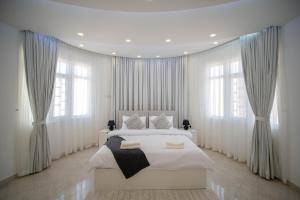 a bedroom with a large white bed with windows at Muscat Stays in Muscat