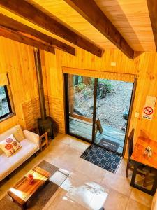 a living room with a couch and a large glass door at Cabaña Alto del Bosque in Coñaripe