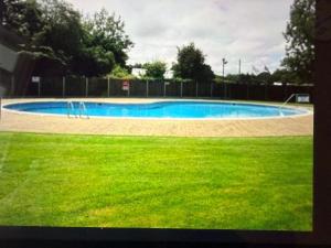 a swimming pool in a yard with green grass at 2 Broadside Chalet Park in Stalham