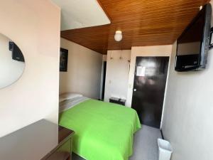 a small bedroom with a green bed and a tv at Hotel Cordillera Real in Sogamoso