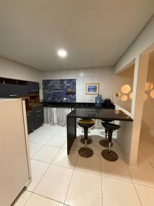a kitchen with a black table and two stools at Japaratinga CENTRO in Japaratinga