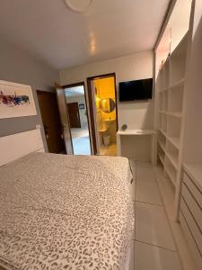 a bedroom with a bed and a tv and shelves at Japaratinga CENTRO in Japaratinga