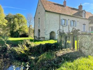 an old stone house with a fence in the yard at Moulin de Bas Couleur in Villedômer