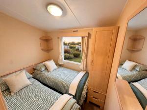 a small room with two beds and a window at Blue Curlew in Scratby