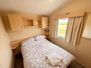 a small bedroom with a bed and a window at Blue Curlew in Scratby