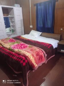 a bed with a blanket on top of it at Lala Ji coasy cottage in Pahalgām