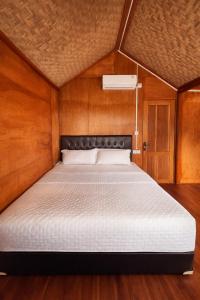a bedroom with a bed in a wooden room at Ocean Fresh Surfhouse in Pulau Sarang