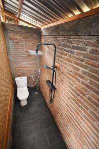 a bathroom with a toilet and a brick wall at Ocean Fresh Surfhouse in Pulau Sarang
