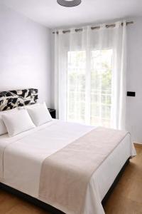 a white bedroom with a large bed and a window at Abril Plaza de España Boutique in Nerja