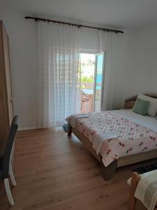 a bedroom with a bed and a window with a balcony at Sea & Mountain View Apartments - Metajna in Metajna