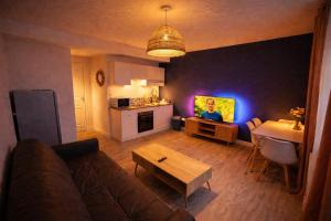 a living room with a couch and a kitchen with violet lights at Le cocon de corbeil in Corbeil-Essonnes