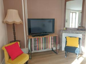 a living room with a television and two chairs at Jolie maison de Potier in Accolay