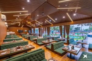 a restaurant with green couches and tables and a pool at Zostel Homes Hampi in Hampi