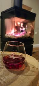 a glass of red wine in front of a fireplace at Hotel Velar in Korçë