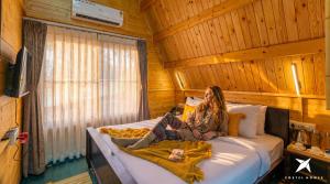 a woman laying on a bed in a wooden room at Zostel Homes Hampi in Hampi