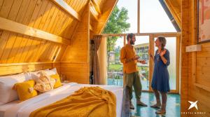 a man and woman standing next to a bed in a room at Zostel Homes Hampi in Hampi