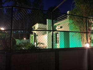 a green and white house behind a fence at night at W Villas in Padinjarathara +5 photos