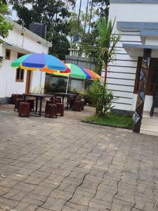 two colorful umbrellas on a patio with tables and chairs at W Villas in Padinjarathara