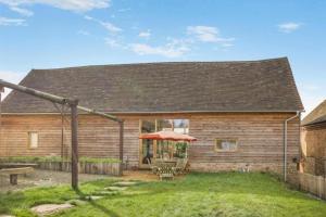 a wooden house with a table and an umbrella at Unique Luxury Barn in Tenbury