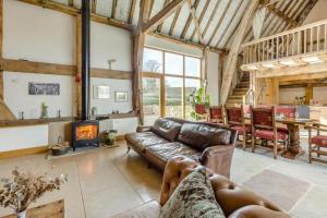 a living room with a leather couch and a fireplace at Unique Luxury Barn in Tenbury