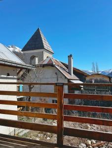 a fence in front of a house with a church at Le chalet des fontaines in Allos
