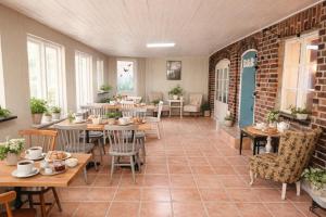 a restaurant with tables and chairs and a brick wall at Tunnby Gårdshotell in Nyhamnsläge