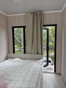a bedroom with a large bed and large windows at Infinity Hotel in Cholpon-Ata