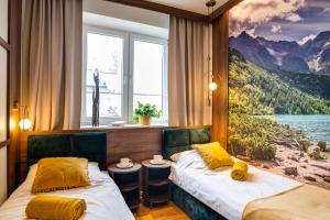 two beds in a room with a painting on the wall at Apartamenty Centrum 50 m od Rynku, FREE PARKING in Nowy Targ