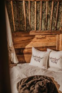 a bed with two white pillows and a wooden wall at Gutonhof in Selva di Val Gardena