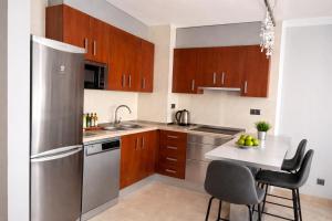 a kitchen with wooden cabinets and a stainless steel refrigerator at Apartamentos Abril in Nerja
