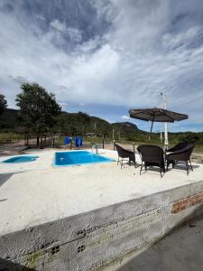 a patio with chairs and an umbrella next to a pool at Chalé Dona Ceci in Cavalcante