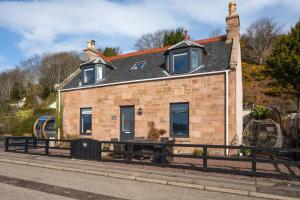 a brick house with a bench in front of it at Shore View Cottage in Inverness