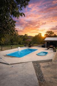 a swimming pool with a sunset in the background at Chalé Dona Ceci in Cavalcante