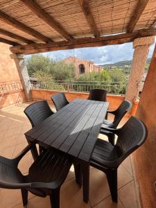 a black dining table and chairs on a balcony at Casetta Alamar in San Teodoro