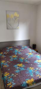 a bed with a blanket with flowers on it at Maison à la mer in Vendres +9 photos