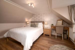 a bedroom with a large white bed and a desk at Shore View Cottage in Inverness