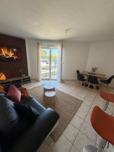 a living room with a black couch and a fireplace at La Pause Larzac- T3 calme-terrasse - Proche Viaduc de Millau in La Cavalerie