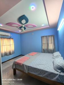 a bedroom with a ceiling fan and blue walls at Dev Homestay kakinada in Kākināda