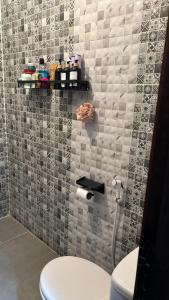 a bathroom with a toilet and a tiled wall at Andalous in Aït Ali