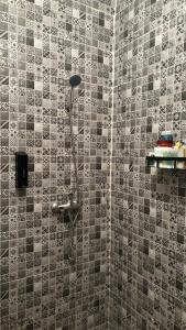 a shower in a bathroom with a tile wall at Andalous in Aït Ali