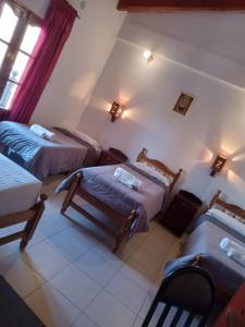 a room with three beds and a chair in it at Hotel Maria Cafayate in San Carlos