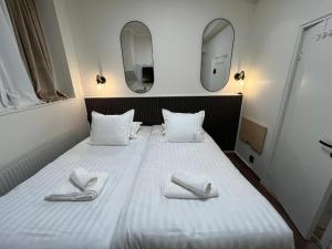 a large white bed with two white slippers on it at Oxbackens Hotell & Café in Västerås +13 photos